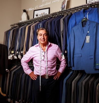 Tailor standing in front of tuxedos