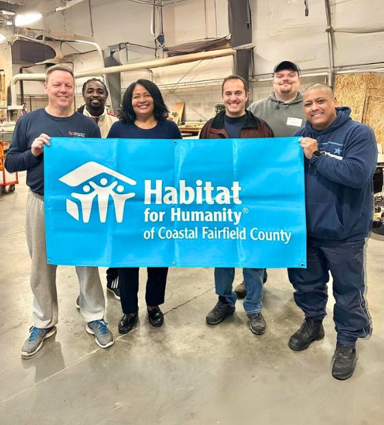 Employees holding banner with Habitat Executive Director