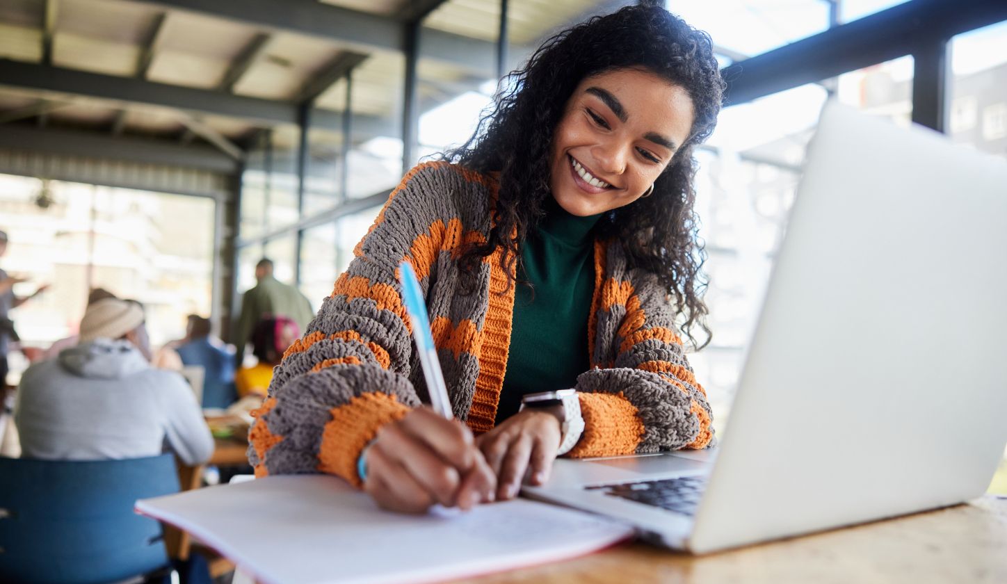 Woman smiling while writing by computer