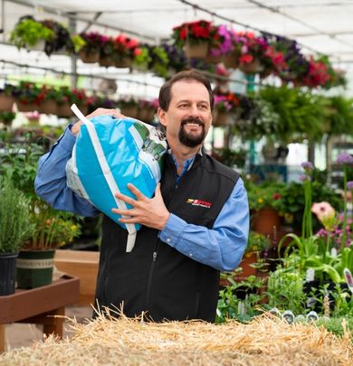 Man carrying a bag of soil in a greenhouse