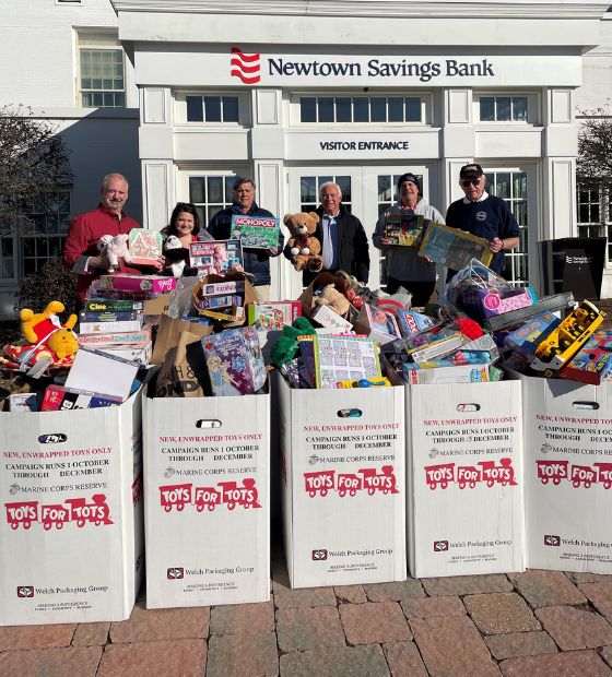 Employees and toys for tots representatives with boxes of donated toys