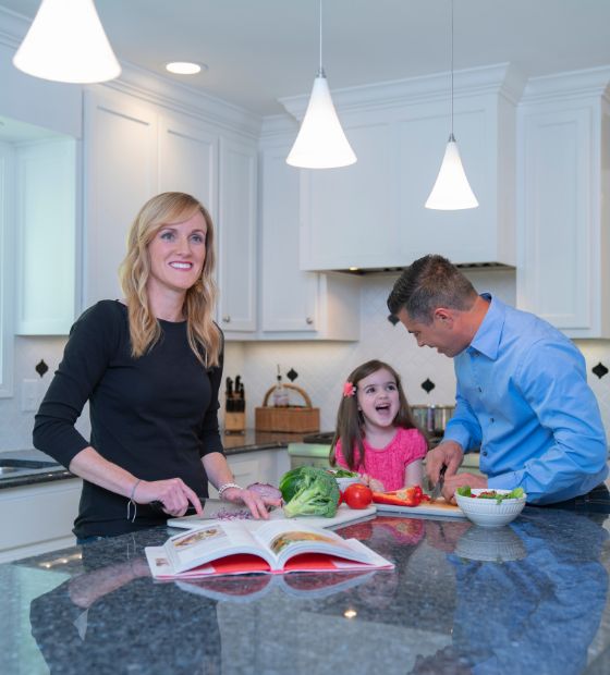 mother and father cooking with daughter in kitchen