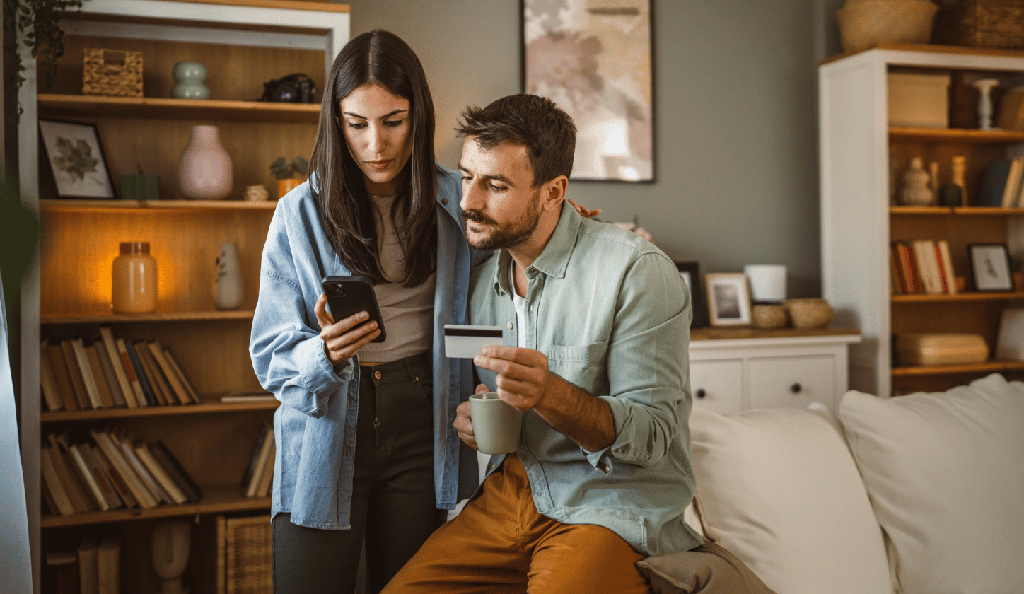 couple staring at phone holding debit card
